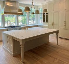 a large kitchen with an island in the middle and two pendant lights hanging from the ceiling