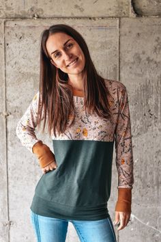 a woman standing in front of a concrete wall with her hands on her hips and looking at the camera