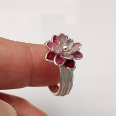 The pink water lily ring is made from high quality recycled 935 silver. The flower has a diameter of 13 millimeters and is hand-painted with a special varnish in different shades of red and pink and baked in the oven. The silver ring band appears to be wound from flower stalks. Nicely packed in a black jewelry box, the water lily ring in widths 54 to 55 can be sent immediately. The pink water lily ring is also available in other ring sizes, it only takes about two weeks. A nice splash of color f Black And Pink Rings, Pink Sterling Silver Flower Ring For Gift, Pink Sterling Silver Flower Ring As Gift, Pink Flower-shaped Sterling Silver Ring, Pink Flower Sterling Silver Ring, Pink Flower Shaped Sterling Silver Ring, Sterling Silver Flower Ring In Pink, Pink Sterling Silver Flower Promise Ring, Sterling Silver Pink Flower Promise Ring