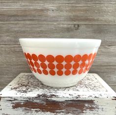 an orange and white bowl sitting on top of a wooden table