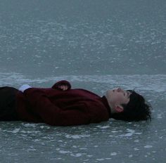 a woman is laying on the ice with her head down and eyes closed as she floats in the water