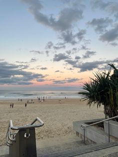 people are walking on the beach at sunset