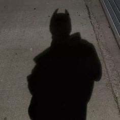 a shadow of a person on the sidewalk with a skateboard in their hand,