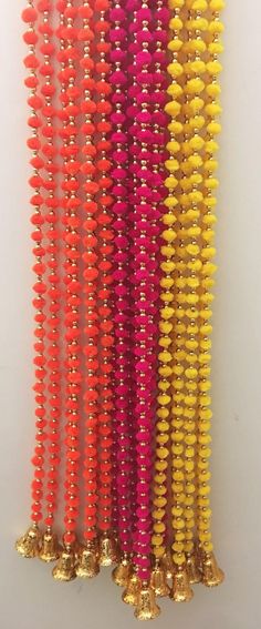 many different colored beads are lined up on a white surface with gold bells in the middle