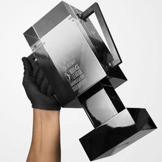 a person wearing black gloves holding up a silver trophy