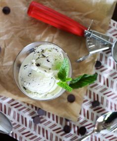 an ice cream sundae with mint and chocolate chips on the table next to it