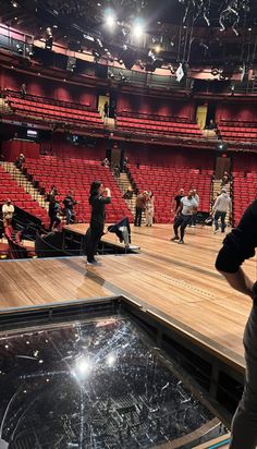 a group of people standing on top of a wooden floor in front of an arena