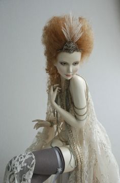 a doll sitting on top of a table next to a white wall and wearing tights