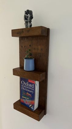 a wooden shelf holding two books and a potted plant on it's side