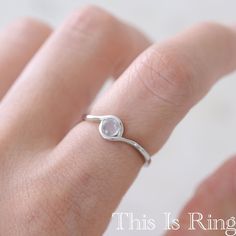 a woman's hand with a ring on it that has a white stone in the middle