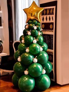 a christmas tree made out of green balloons and gold stars on it's top