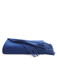 a blue blanket folded on top of a white surface with fringes in the middle