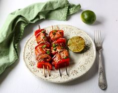 a white plate topped with kebabs next to a lime