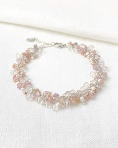 This piece is a soft, feminine bouquet for your arm. In this lovely piece, I have clustered together a beautiful collection of tiny gemstones. Topaz rondelles, in various shades of pink, are accented with sparkling crystal quartz, luminous tiny seed pearls, and subdued peach moonstone. The soft shades of pink are neutral in tone, making this a versatile piece that can be worn with a variety of outfits. Each petite gemstone and pearl is individually wire-wrapped in sterling silver, a process that takes several hours of meticulous work. The result is a gorgeous piece that you will love to wear or gift. Bracelet length: 7 inches plus 1 inch extender Materials: pink topaz, cultured freshwater pearls, crystal quartz, peach moonstone, sterling silver Unwrap more than just a gift. This product co Elegant Pink Crystal Bracelet With Sparkling Stones, Elegant Crystal Bracelets With Gemstone Beads, Elegant Rose Quartz Crystal Bracelet, Elegant Rose Quartz Gemstone Beaded Bracelets, Delicate Beaded Crystal Bracelet, Elegant Rose Quartz Gemstone Beaded Bracelet, Dainty Pink Beaded Bracelets For Wedding, Elegant Silver Rose Quartz Crystal Bracelet, Elegant Beaded Rose Quartz Crystal Bracelet