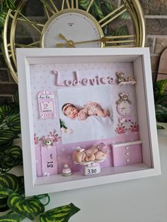 a baby's photo frame with a clock in the background