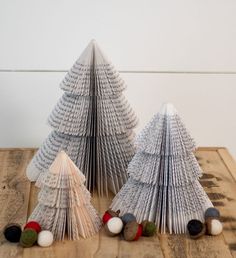 three folded paper christmas trees sitting on top of a wooden table next to each other