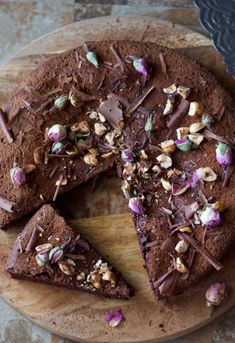 a chocolate cake on a wooden plate with one slice cut out and the other half eaten