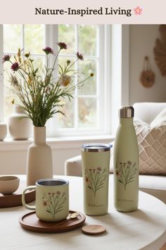 a table topped with two cups and a vase filled with flowers