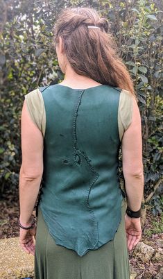 The Wanderer Buckskin Vest in Emerald Green.This vest is currently available.This is a soft and supple green deerskin vest. Hand sewn and patched worked with contrasting thread for interesting detail. The vest closes with a row of antler buttons. The sides lace together, and are thus greatly adjustable, and reinforced with grommets. This leather top is unisex and is flattering for men and women size medium through large. Great for wearing next to the skin, but adjustable enough that you can easi Green Sleeveless Vest With Patchwork, Green Sleeveless Patchwork Vest, Fitted Sleeveless Patchwork Vest, Fitted Sleeveless Vest For Larp, Antler Buttons, Leather Choker Collars, Leather Sketchbook, Star Goddess, The Wanderer