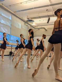 a group of dancers in black leotards and ballet shoes, with their backs turned to the camera