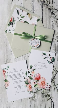 the wedding stationery is laid out on top of an envelope and some flowers are tied to it