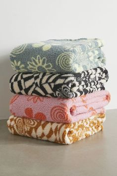 four towels stacked on top of each other in different colors and patterns, all folded neatly