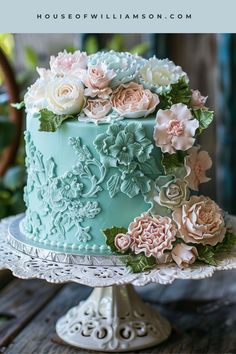 a blue cake with flowers on it sitting on top of a table