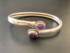 925 Sterling Silver Amethyst Bangle Stylish easy-wearing bangle Solid sterling silver bangle with amethyst gemstones 2 bezel set amethyst cabochon stones sit at the ends of the bangle Ends of bangle can be pulled apart for ease of putting on and taking off Highest quality guaranteed 925 Sterling Silver - 92.5% pure silver Specifications:    Color: Silver & Dark Purple  Material: 925 Sterling SIlver & Amethyst  Dimensions of gemstones: 8 mm x 6 mm approximately Inner Dimensions: 60 mm x 47 mm approximately Outer Dimensions of bangle: 65 mm x 55 mm approximately Width of Bangle: 5 mm approximately Weight: 12.7 grams approximately Package Includes: 1 x sterling silver gemstone bangle with complimentary jewellery pouch Silver Amethyst Bangle Bracelets, Silver Amethyst Bangle Bracelet, Silver Amethyst Gemstone Bangle, Purple Gemstone Bangle For Formal Occasions, Formal Purple Gemstone Bangle, Sterling Silver Amethyst Bracelet With Gemstone, Amethyst Gemstone Bangle, Elegant Silver Amethyst Bangle, Purple Amethyst Bangle