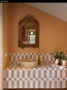 a bathroom sink sitting under a mirror next to a vase with flowers on top of it