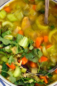 a bowl full of soup with carrots, celery and other veggies