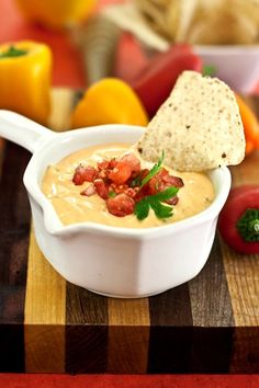 a white bowl filled with soup and chips on top of a wooden cutting board next to vegetables