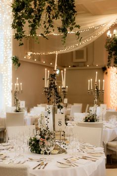 the table is set with white linens, candles and greenery for an elegant wedding reception