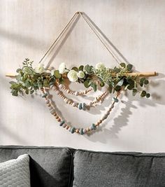 a living room with a gray couch and wooden beaded garland hanging on the wall