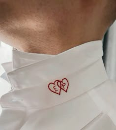 a close up of a person wearing a white shirt with two hearts on the chest