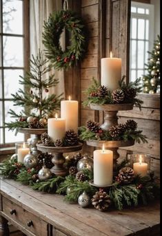 christmas candles are arranged on a table with pine cones