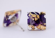 a pair of purple and gold earrings on a white background