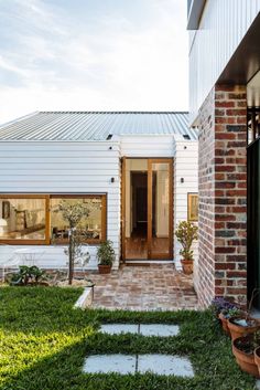 a brick house with potted plants on the front lawn and an entry way leading to it