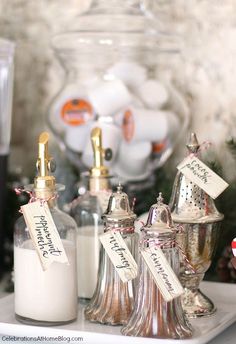 some bottles are sitting on a table with christmas decorations around them and tags hanging from them