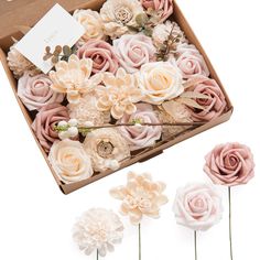 pink and white flowers are in a box with some tags on it, along with three smaller ones