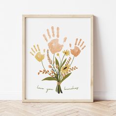 a hand print with flowers and leaves on the bottom is in front of a white wall