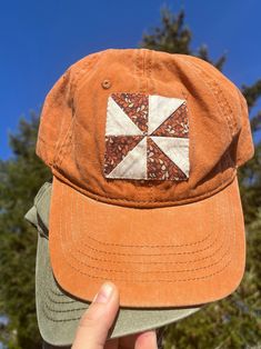 a person holding up a brown hat with a patchwork design on the front and side