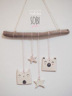 three ceramic ornaments hanging from a wooden branch on a wall with the words sobi written above them