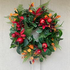 a wreath with red apples and green leaves on a white wooden background, hanging from the side of a door