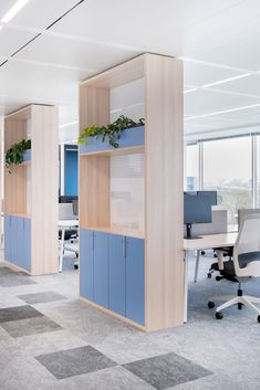 an office cubicle with blue cabinets and plants on the shelves in front of it