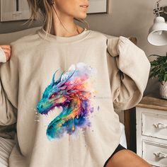 Watercolor Dragon Sweatshirt Unisex Crewneck Sweatshirt Ideal for any situation, a unisex heavy blend crewneck sweatshirt is pure comfort. These garments are made from polyester and cotton. This combination helps designs come out looking fresh and beautiful. The collar is ribbed knit, so it retains its shape even after washing. There are no itchy side seams on these sweaters. Unisex, soft, and high-quality Heavy Blend Crewneck Sweatshirt - Gildan 18000 💜 Medium-heavy fabric 8.0 oz/yd² 💜 Loose fit 💜Runs true to size 💜50% cotton, 50% polyester 💜Sewn-in label   CARE INSTRUCTIONS Follow our care instructions to look after your custom-printed products. 💜Machine wash: warm (max 40C or 105F) 💜Non-chlorine: bleach as needed 💜Tumble dry: medium heat 💜Do not iron 💜Do not dry clean   💜Fit: Crew Neck T-shirt With Watercolor Print, Multicolor Long Sleeve Tops With Custom Print, Casual Crew Neck Sublimation Design With Custom Artwork, Casual Multicolor Tops With Custom Artwork, Multicolor Crew Neck Shirt With Printing, Casual Long Sleeve T-shirt With Custom Artwork, Multicolor Crew Neck Sweatshirt With Screen Print, Artistic Multicolor Crew Neck Shirt, Multicolor Graphic Print Long Sleeve Top