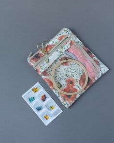 a small purse with some stickers on it and a sewing kit in front of it