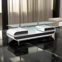 a modern coffee table with glass top and black base, in front of a window