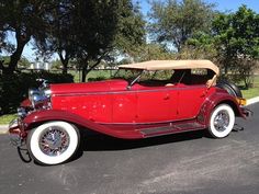 an old red car is parked on the street