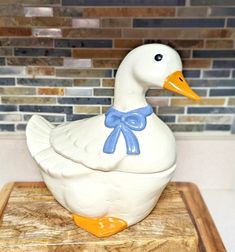 a ceramic duck sitting on top of a cutting board in front of a tile wall