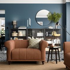 a living room filled with furniture and a round mirror on the wall over a coffee table